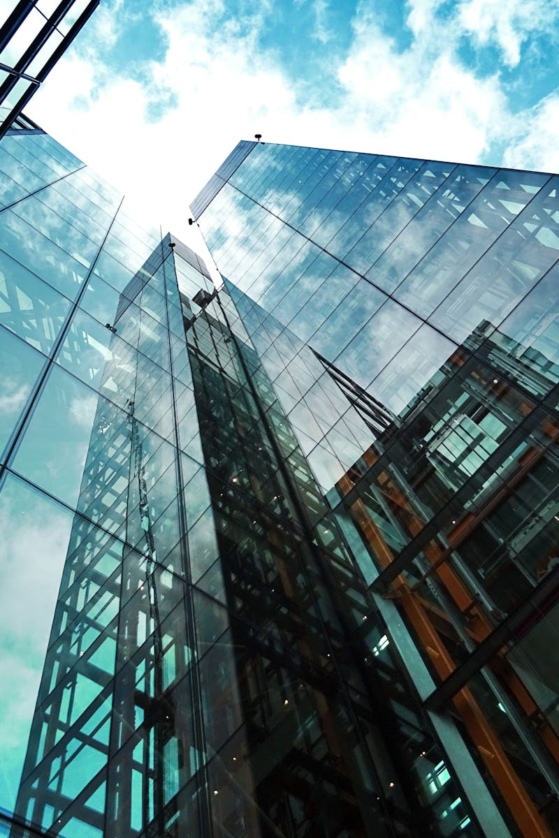 A striking view of a modern glass skyscraper reflecting the sky and clouds.
